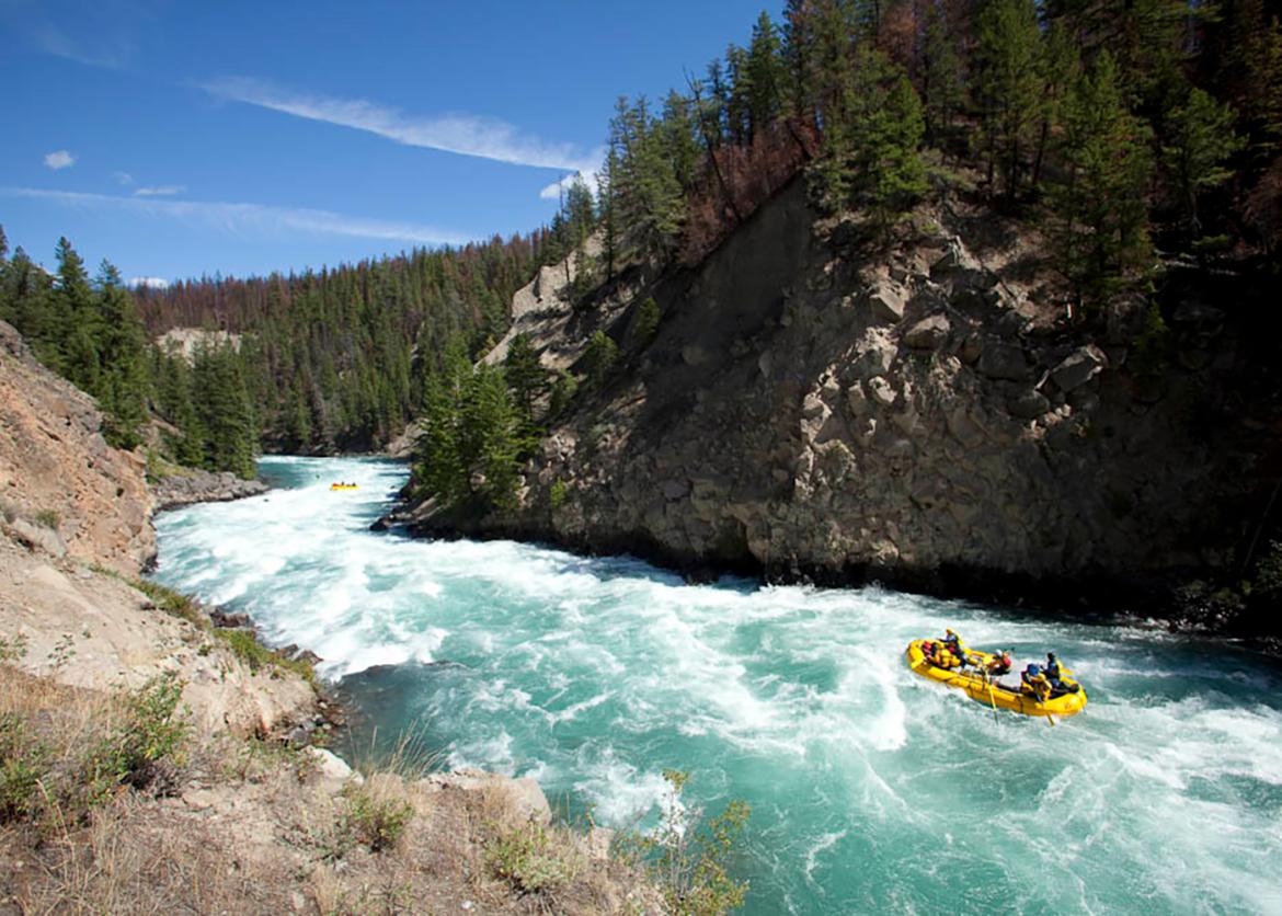 People white water rafting on blue river with rapids