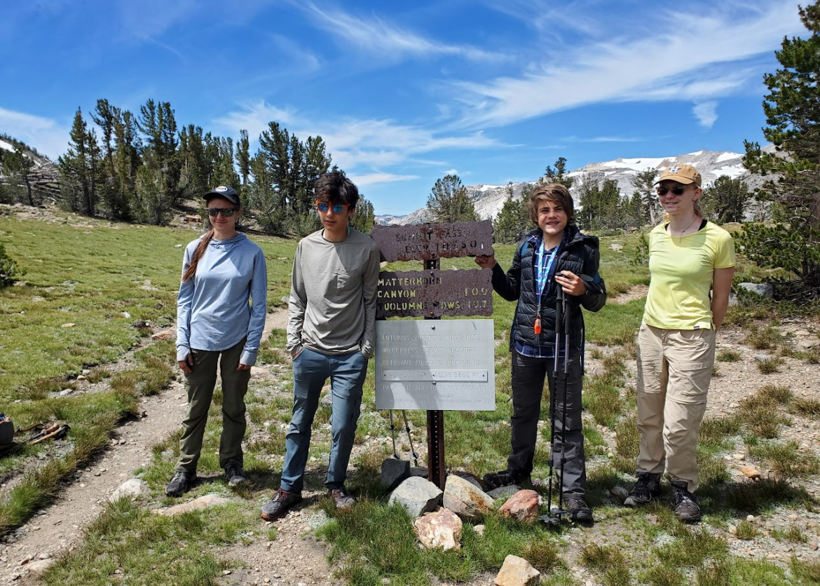 A group of teens standing next to the trail sign