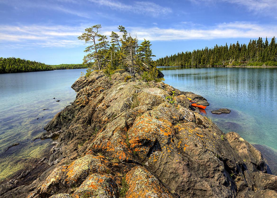 A ridge of rocks surrounded by water. A kayak is parked and tucked into one side.