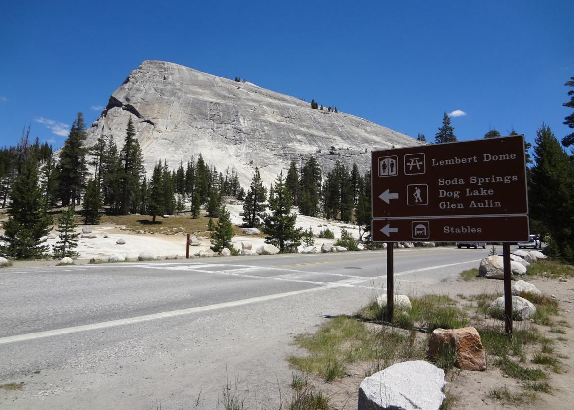 A road side sign in Yosemite National Park, rock formations in the background