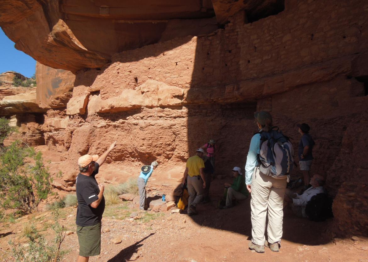 People standing around, observing and pointing at different angles under the canyon