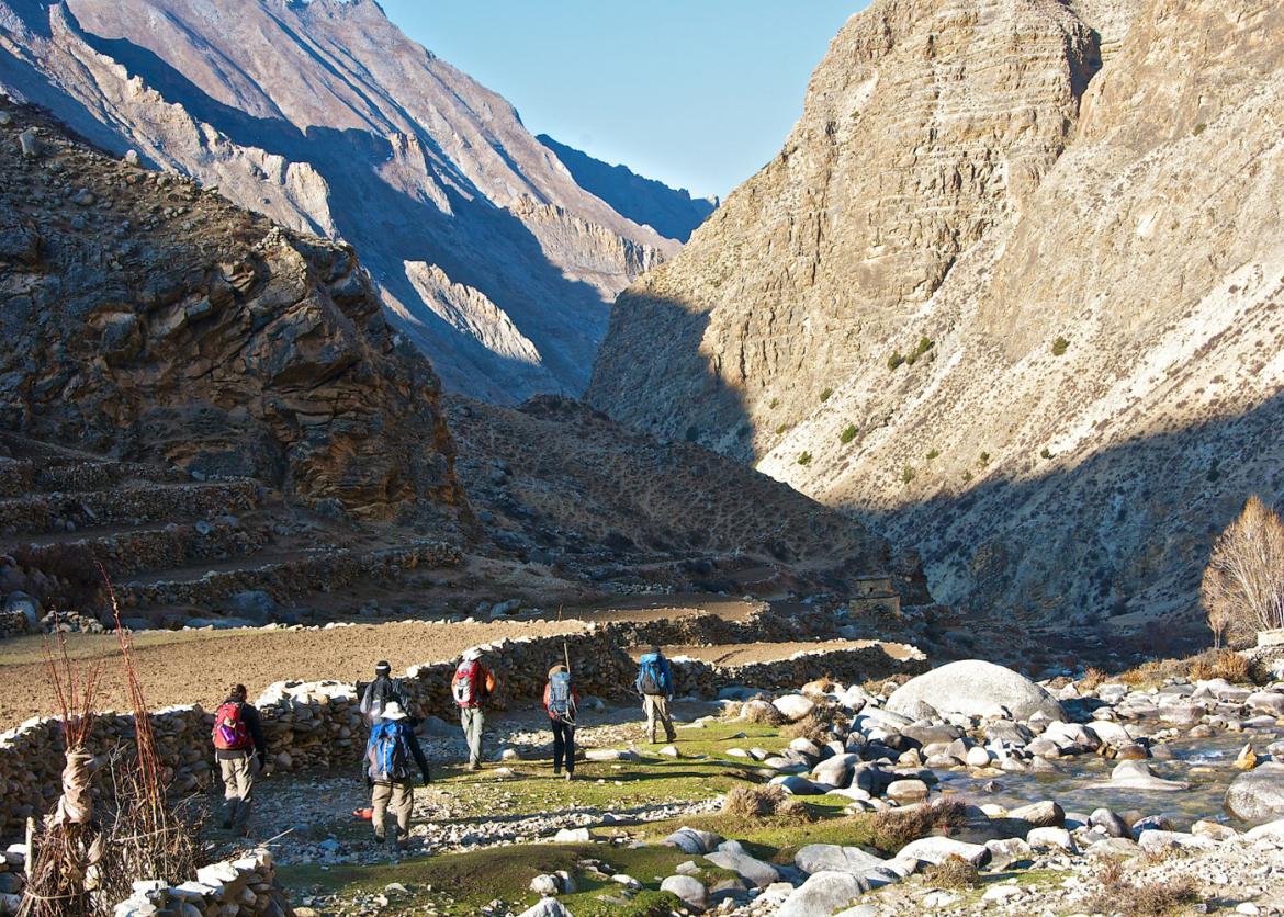 Six people walk toward a rocky gulch.