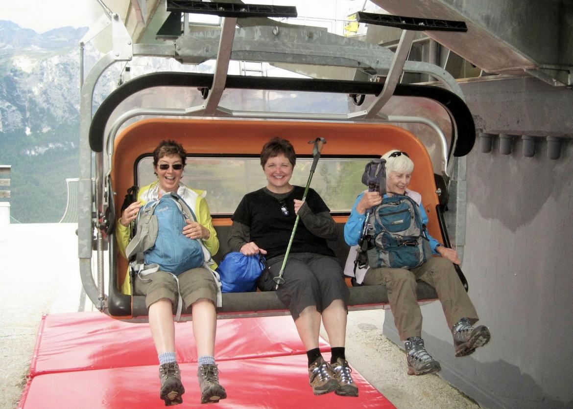Three smiling people on a ski lift at the loading station.