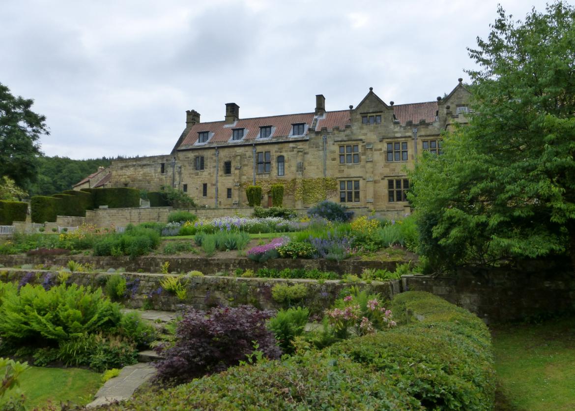 An old fashioned stone building overlooking a garden.