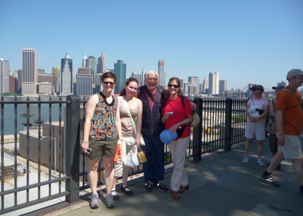 Four smiling people pose in front of a view of the New York City skyline.