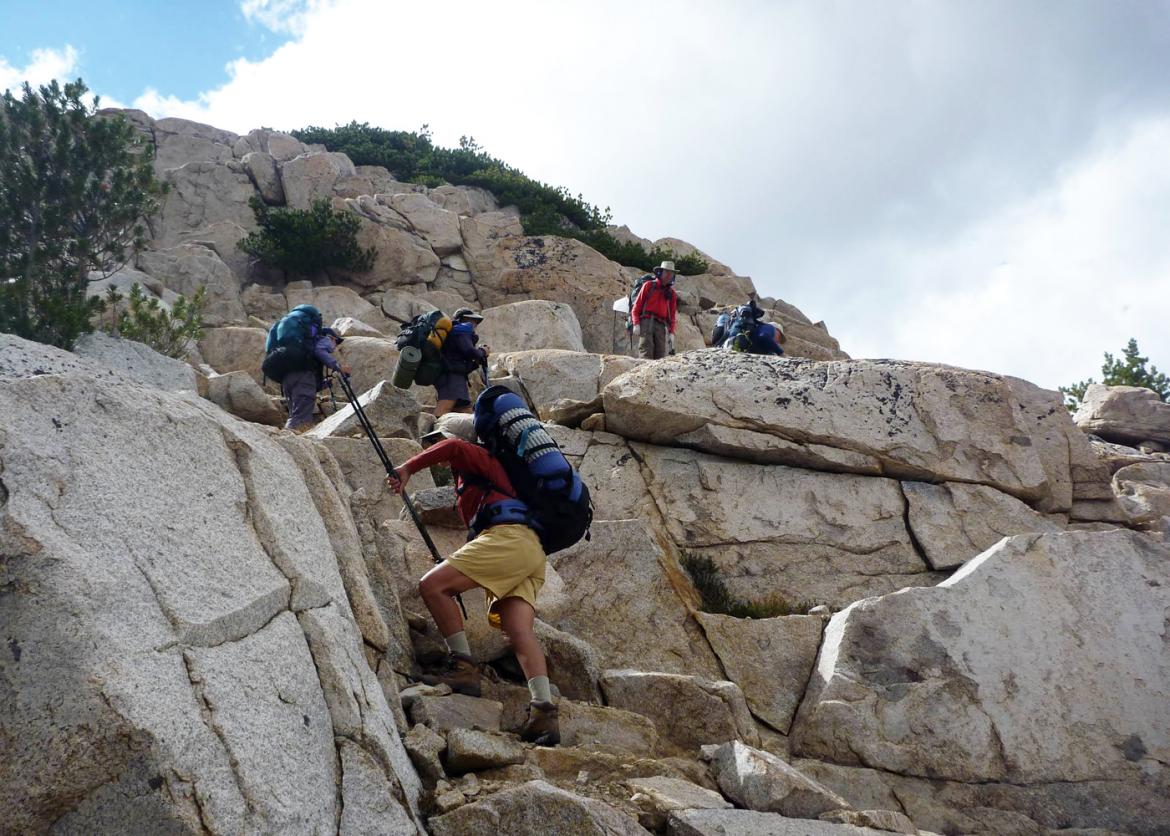 Hikers making their way up as they climb boulders.