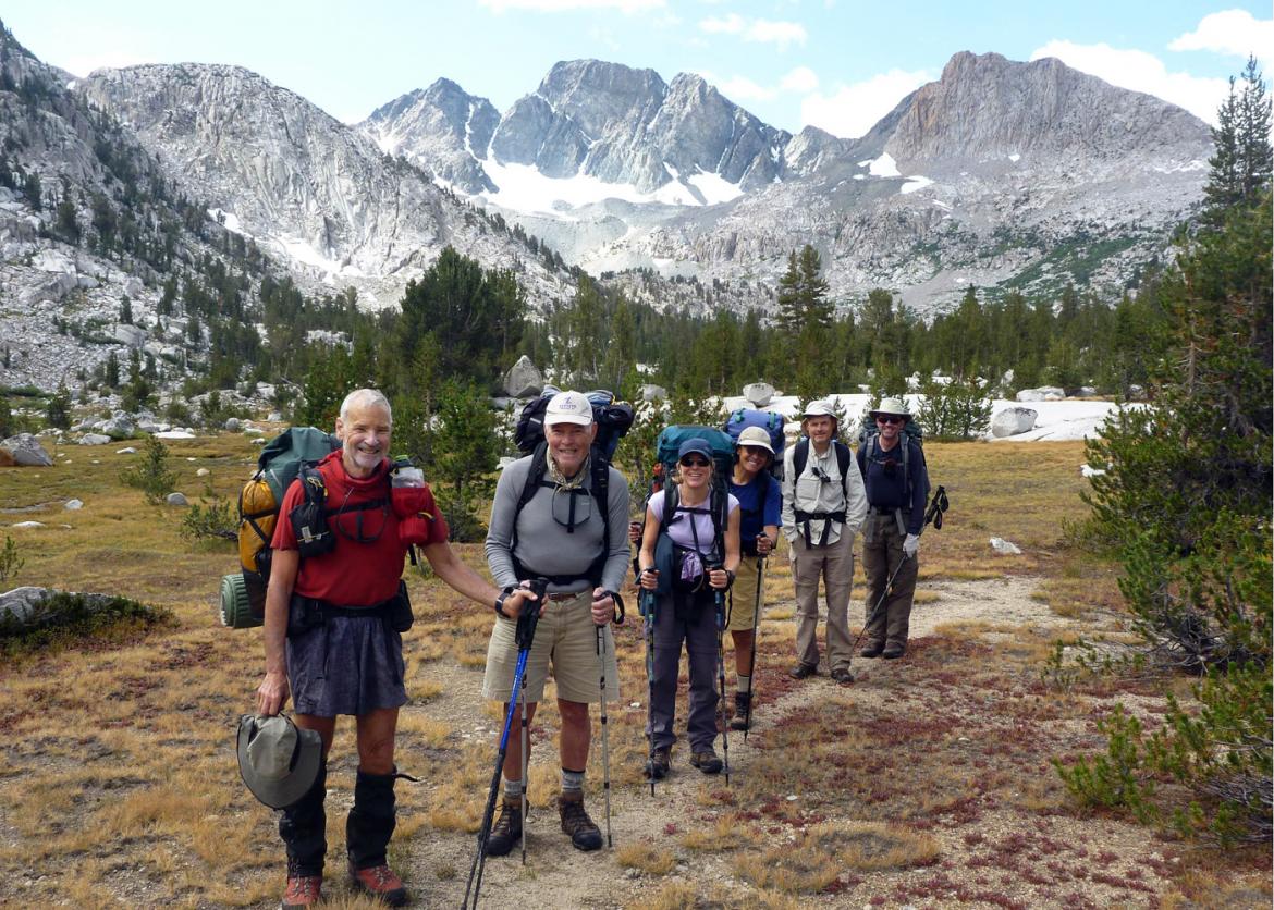 A group of hikers lined up on the trail, smiling at the camera.