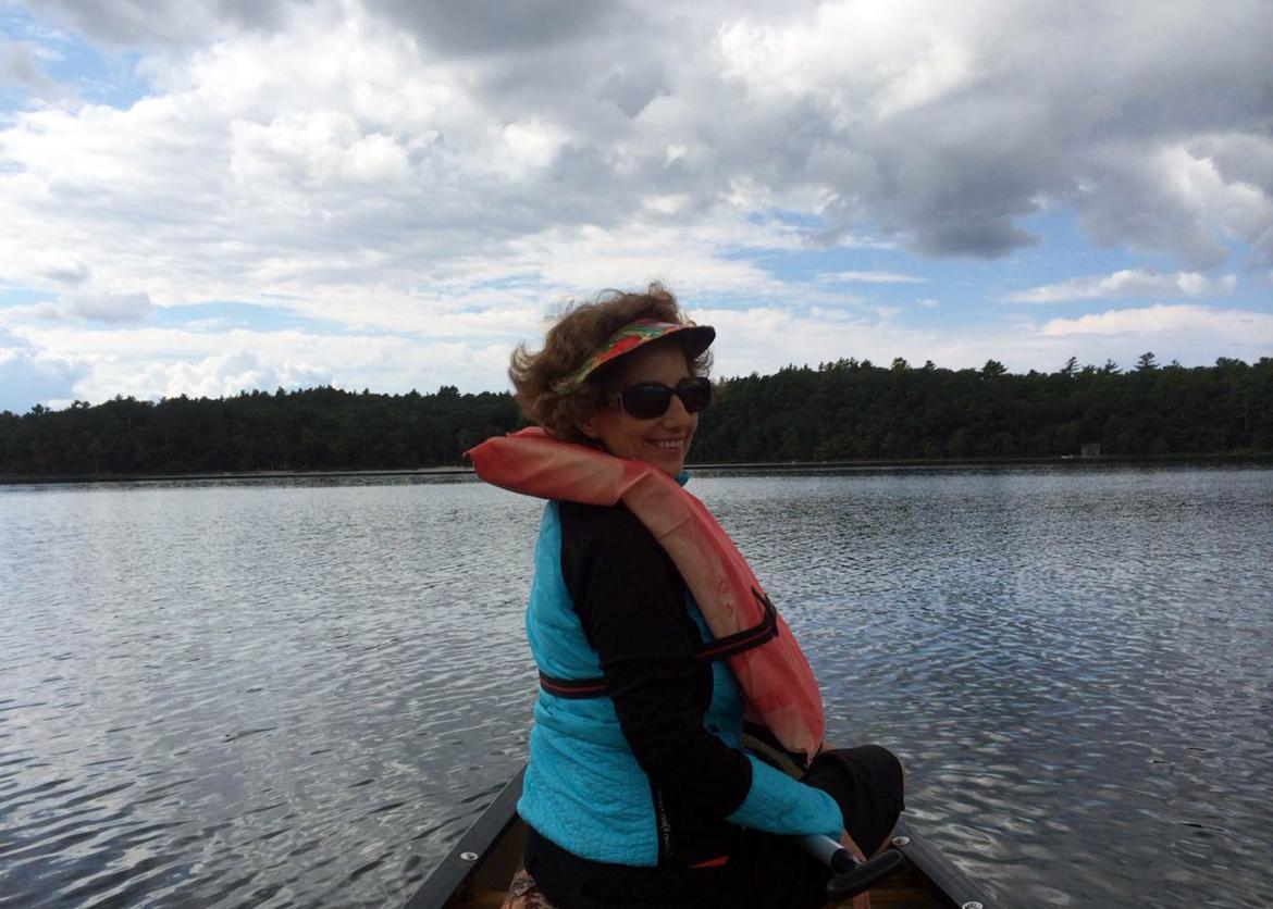 A woman in sunglasses, turning around in the canoe.