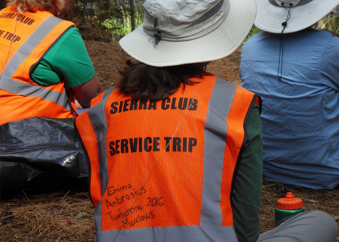 A participant in a neon vest, the back reads "Sierra Club Service Trip." The words "Emma Ambrosius Twolumne 2016 Mcarlows" are written in sharpie.