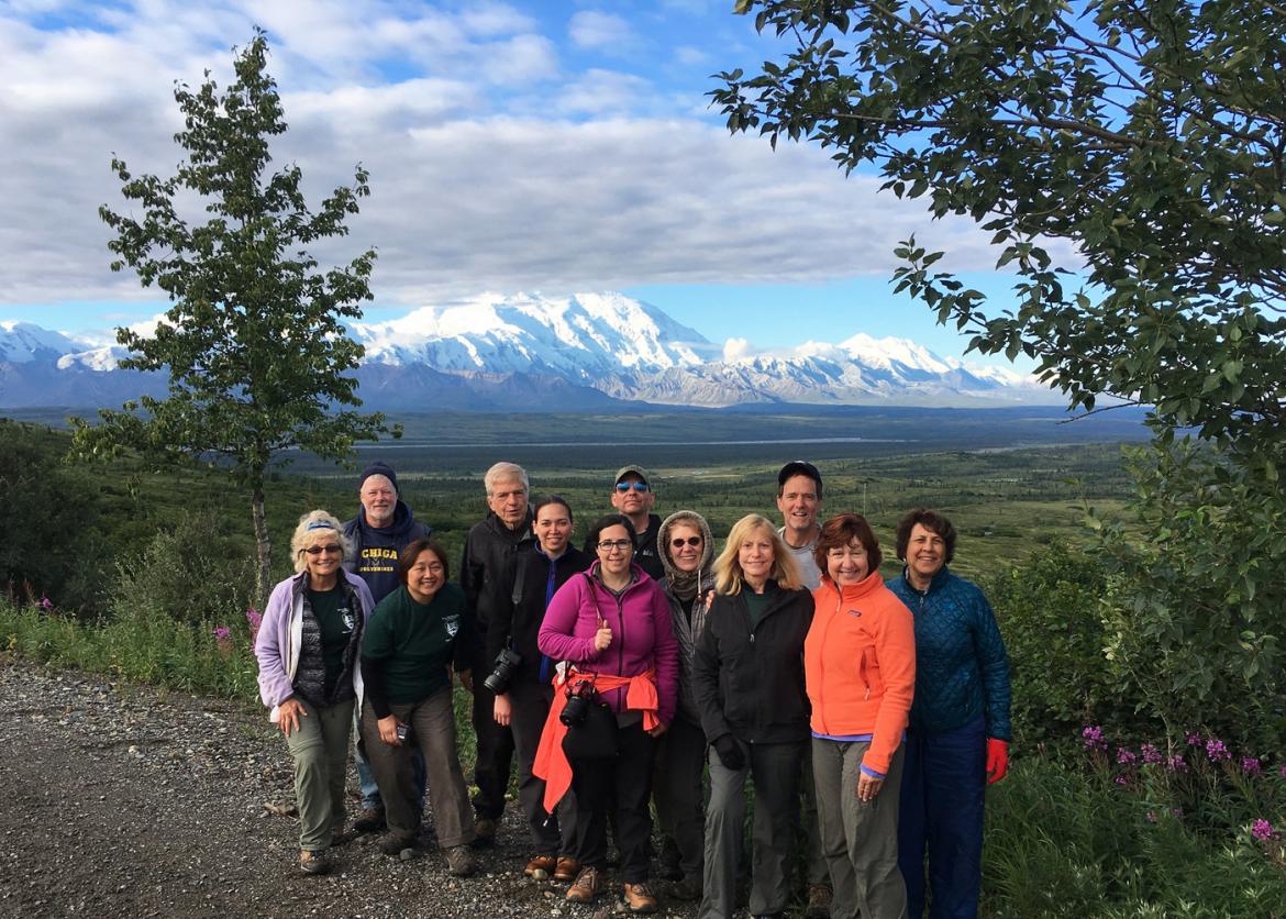 Participants smiling and posing as a group in front of a view of mountains.