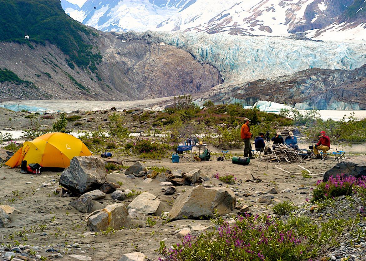 People setting up tents in the flat ground of the mountain.