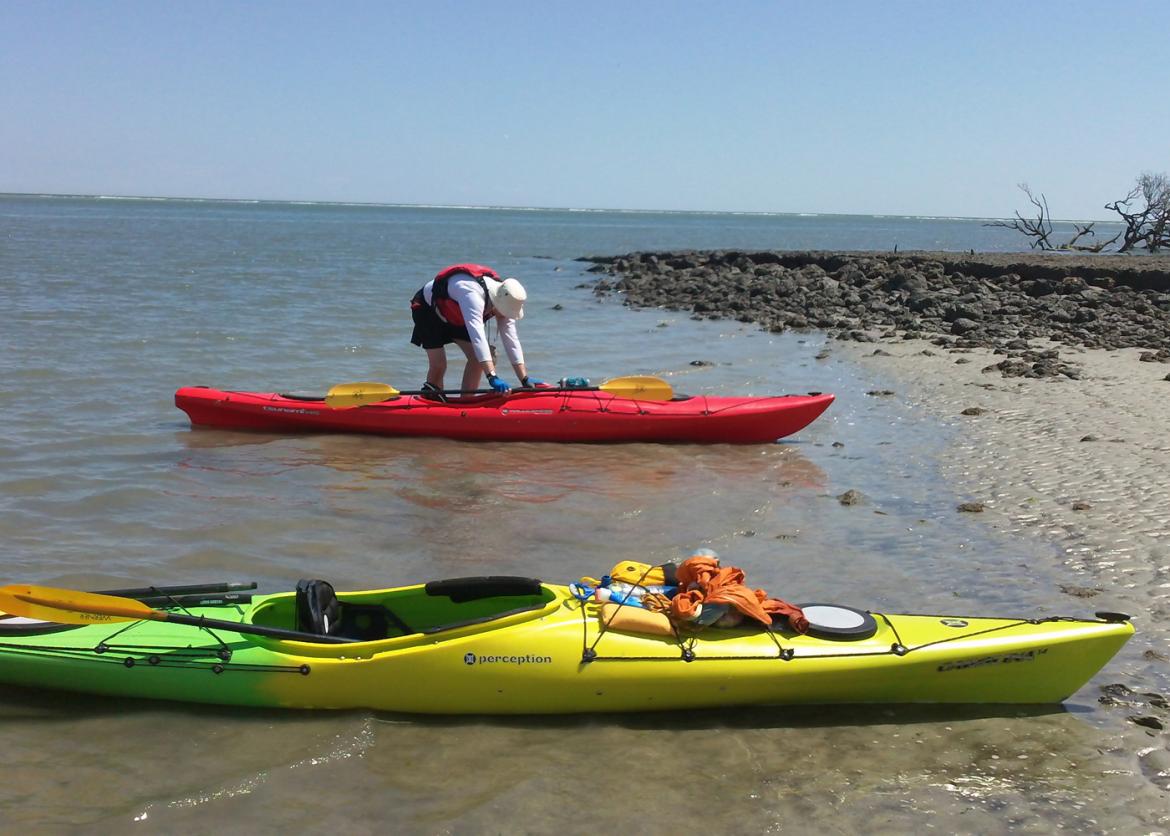 A person beaches their kayak next to another.