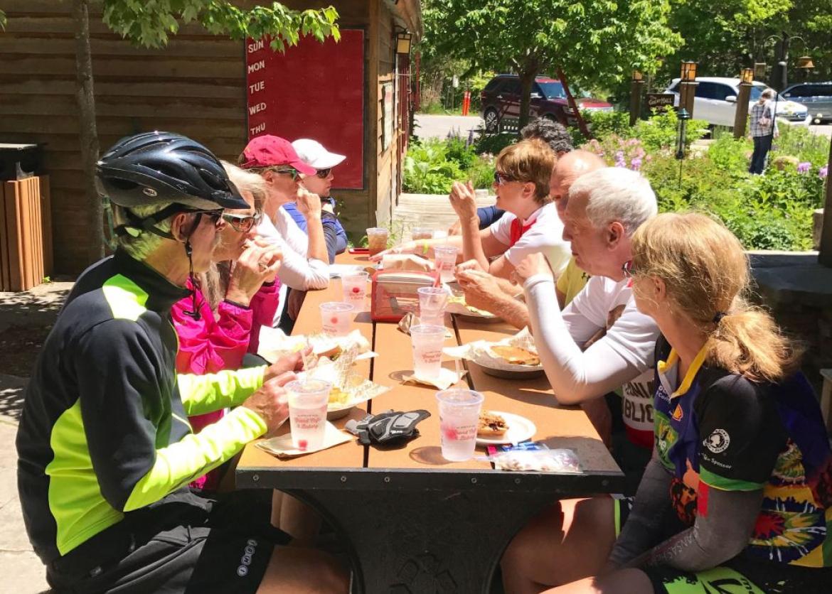 A group of bikers taking a meal break next to a lodge in a resting area.
