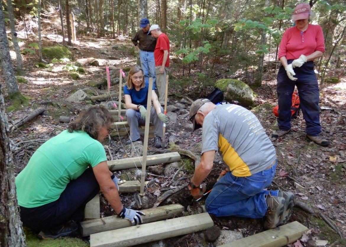 A group of people building a bridge with logs.