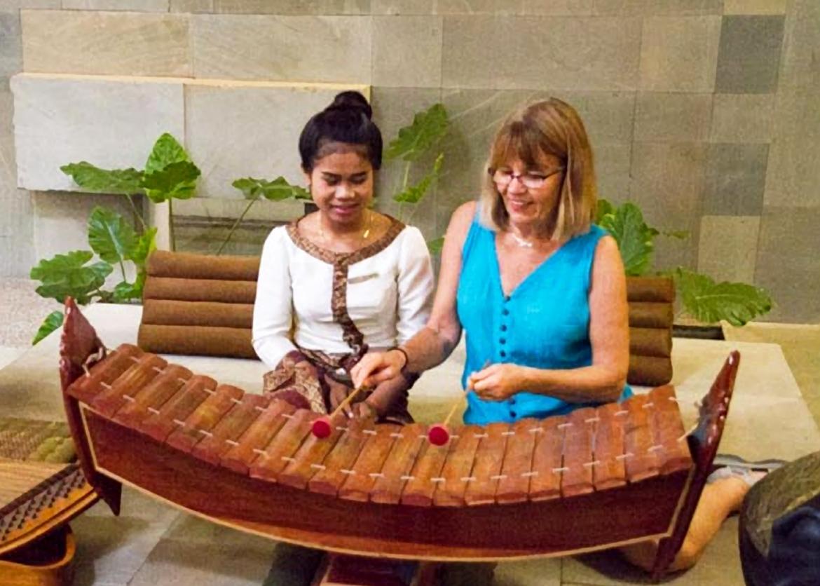 A Vietnamese woman teaches a white woman how to play the xylophone.