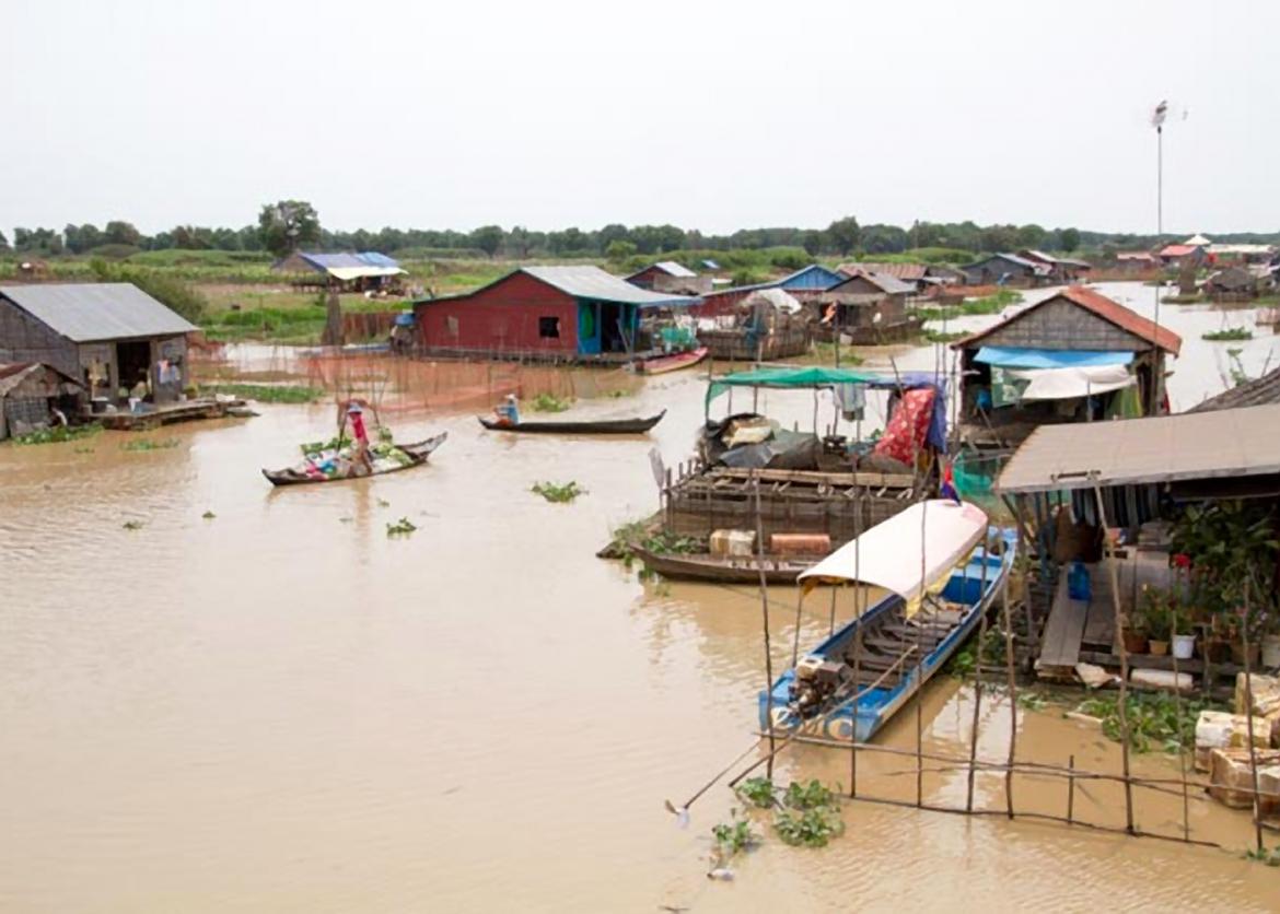 Boats float between houses resting on brown water.