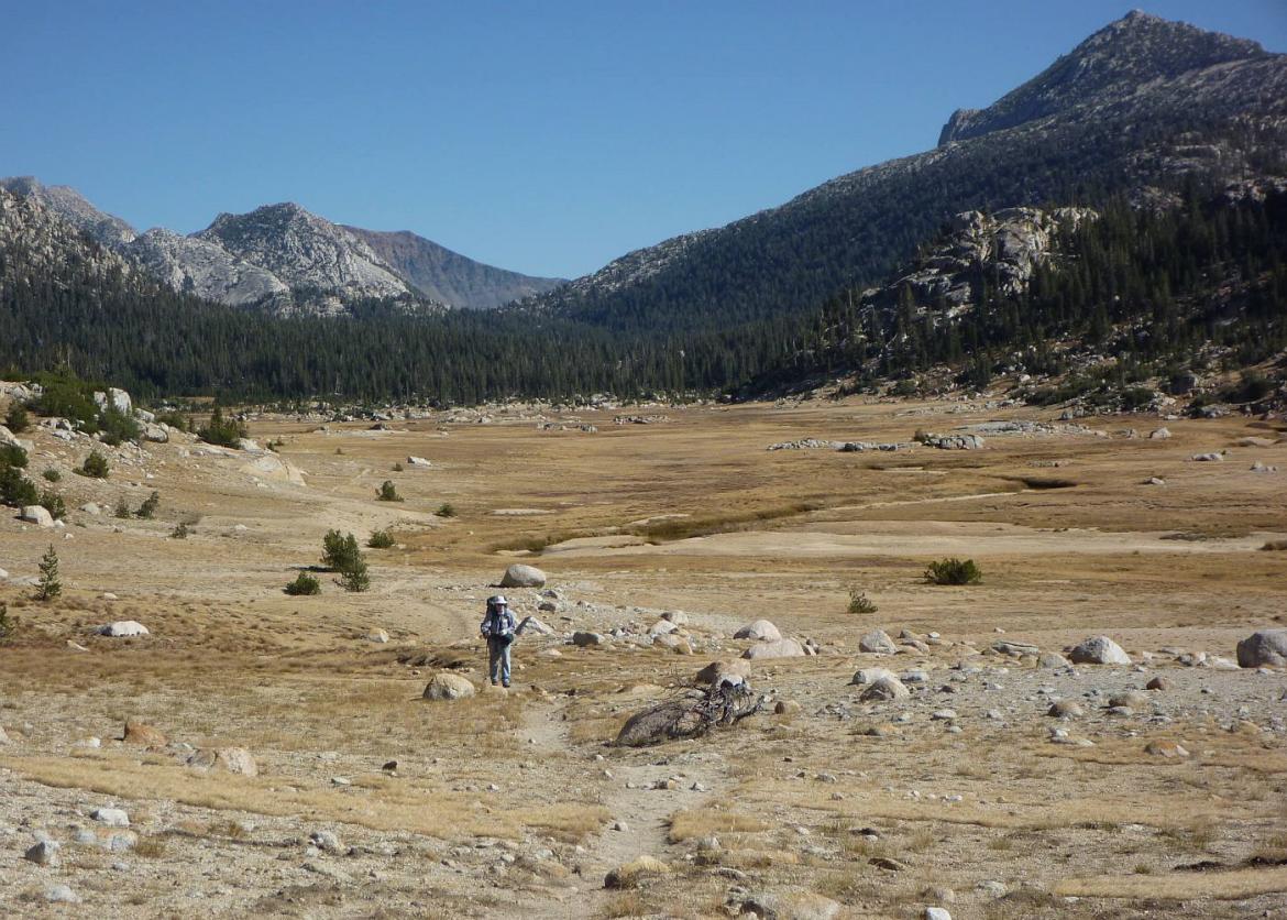 A empty area with a single hiking trail with a hiker making his way up.
