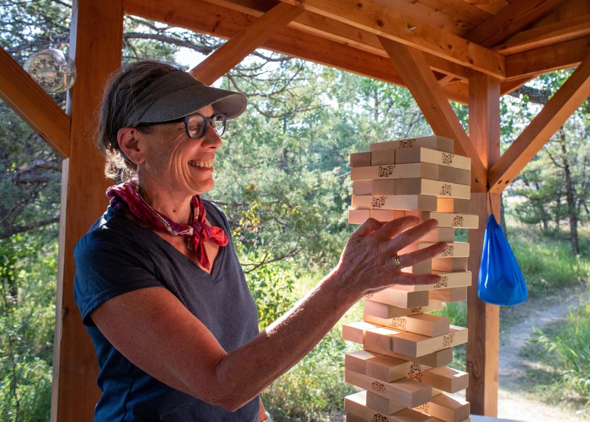 A woman playing jenga in an outdoor pavillion.