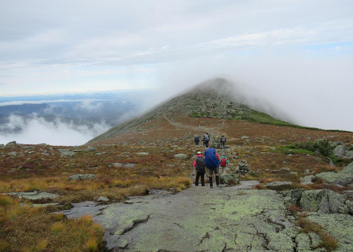 Trip participants hiking in New Hampshire's Presidential Range with clouds rolling in over the peak