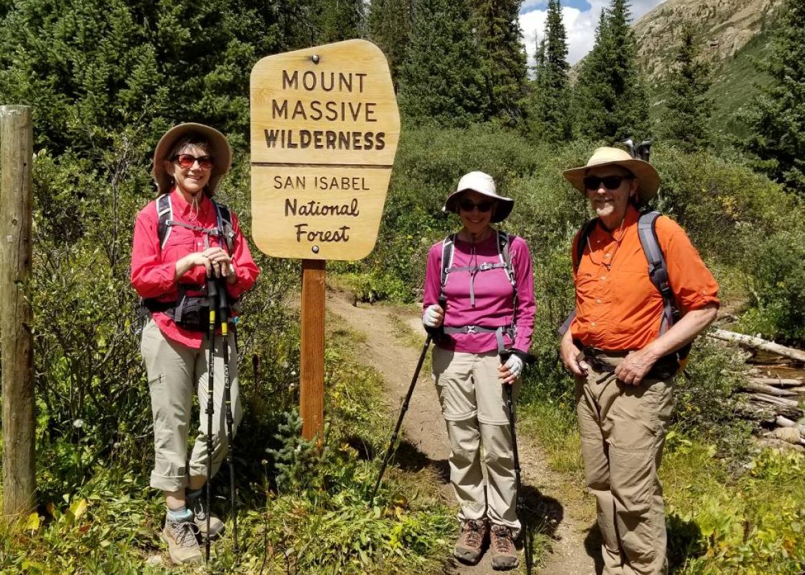 Three hikers standing next to a sign that says "Mount Massive Wilderness".