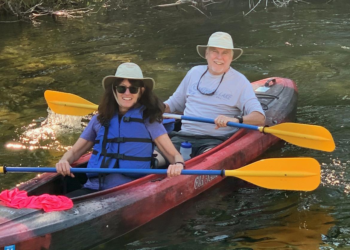 A couple kayaking and smiling.