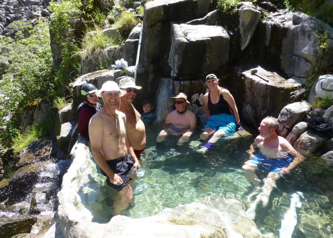 Seven smiling people relaxing in a pool of clear water.