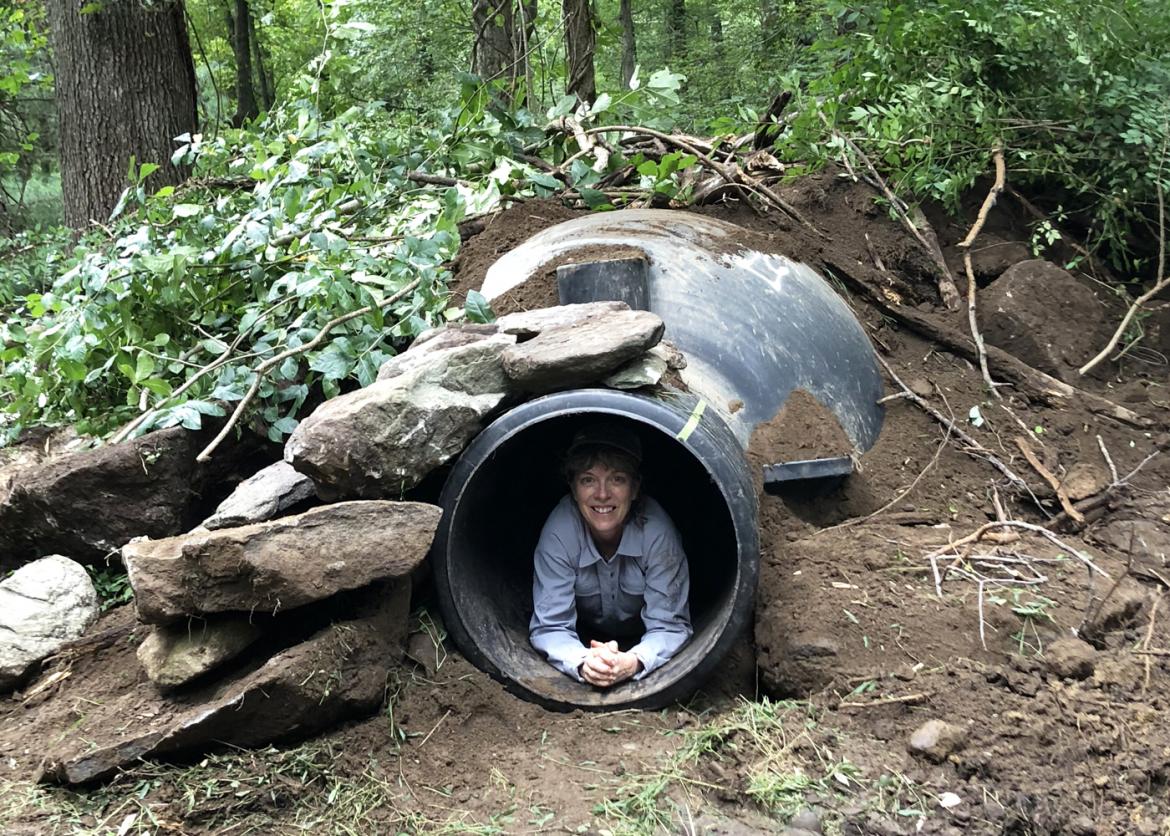A woman inside a tunnel hole, smiling as she's crouching down.