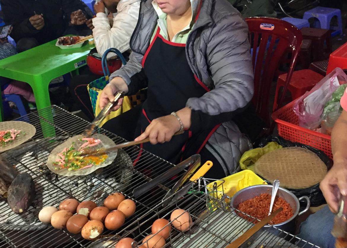 A woman grilling street food.