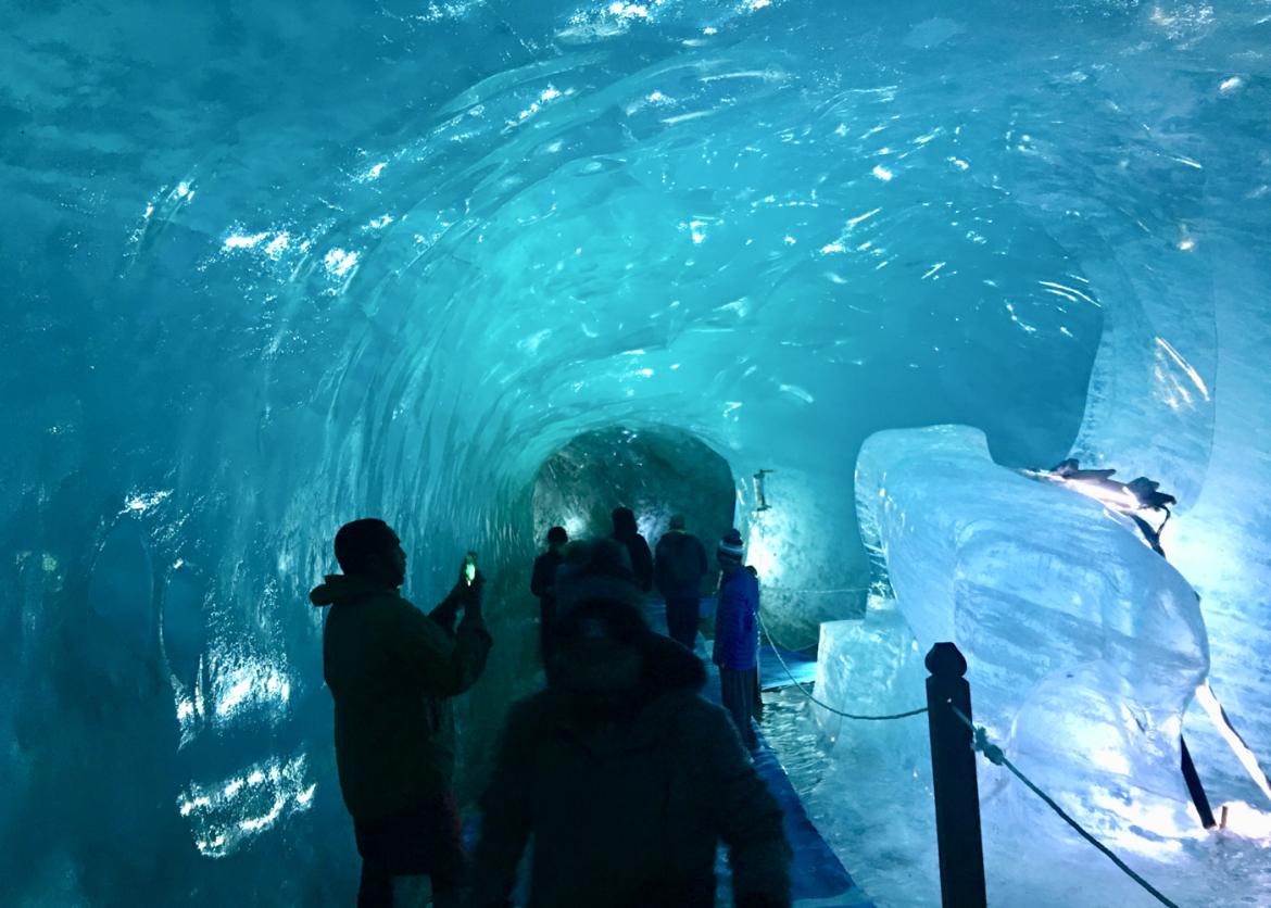 A hallway made of ice. People walk through taking pictures.
