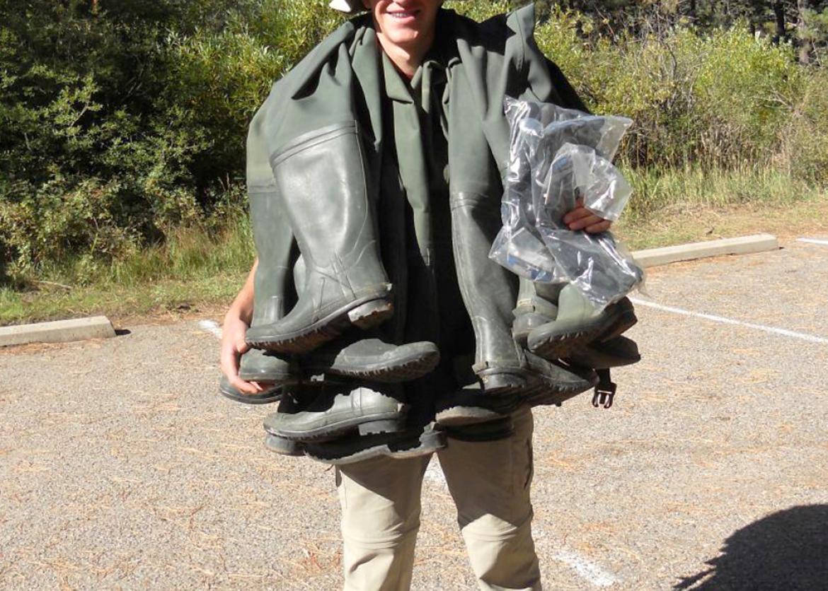 A man carrying lots of boots on his shoulders.
