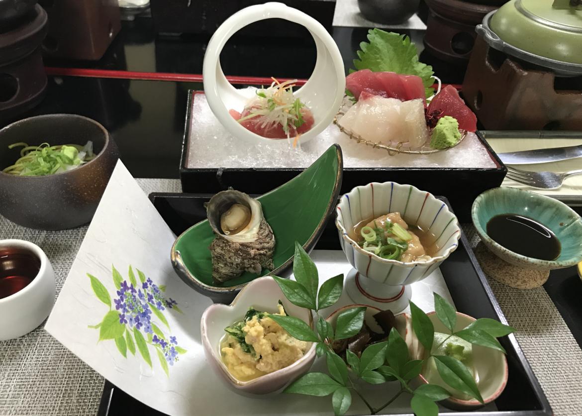 A meal served in an array of ornate saucers. Saucers of raw fish rest on a bed of ice.