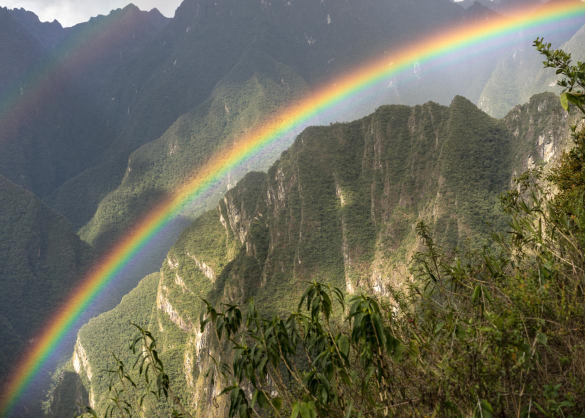 A double rainbow over a forested mountain ridge.