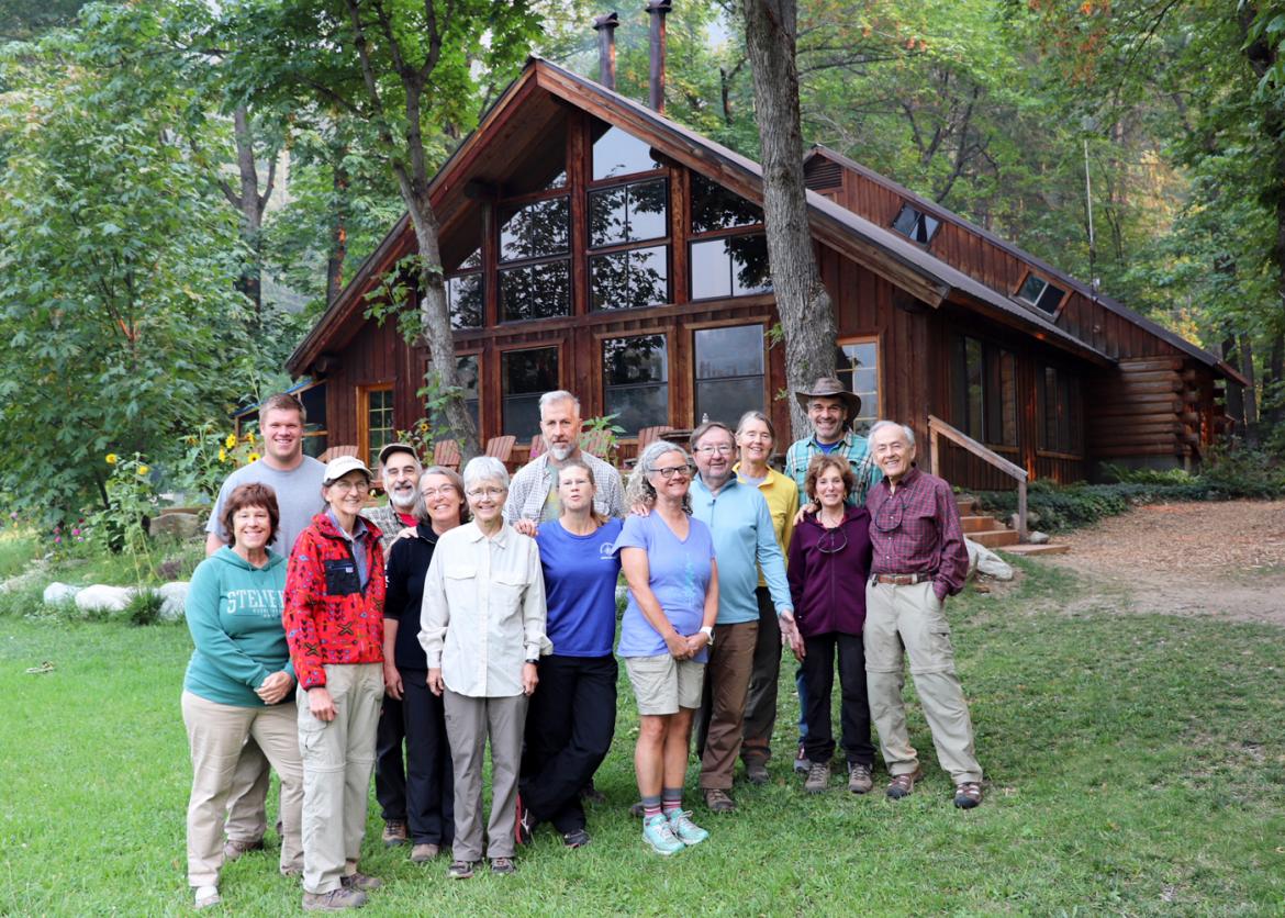 A group smiling and posing for the photo with the lodge in the back
