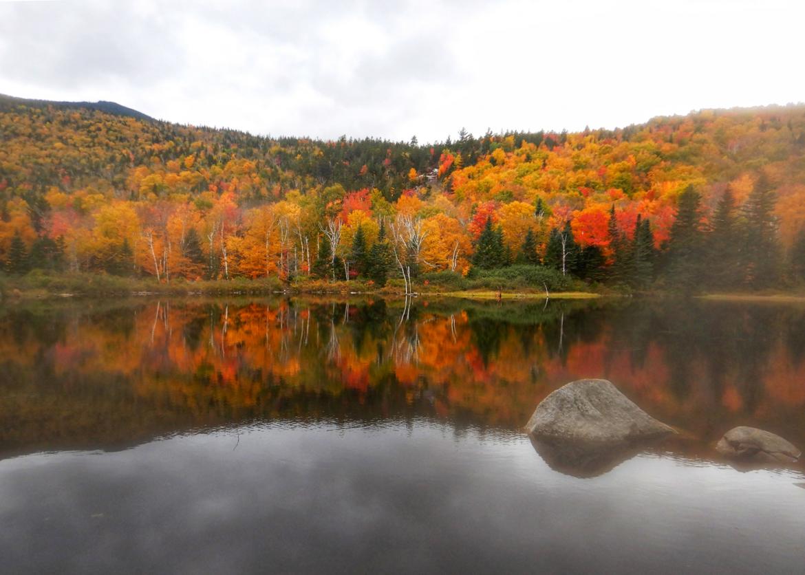 A lake reflecting the red, orange, and yellow trees.