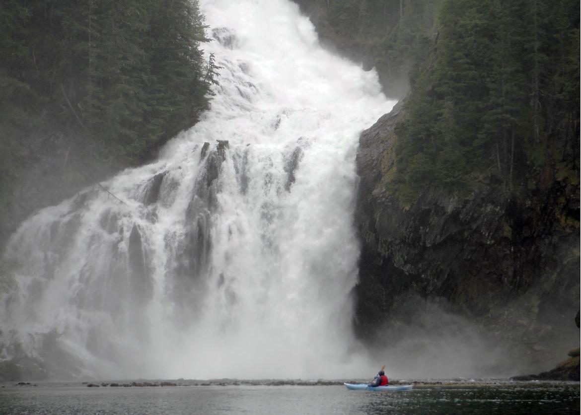 Kayaker in front of large waterfall in Prince William Sound, Alaska
