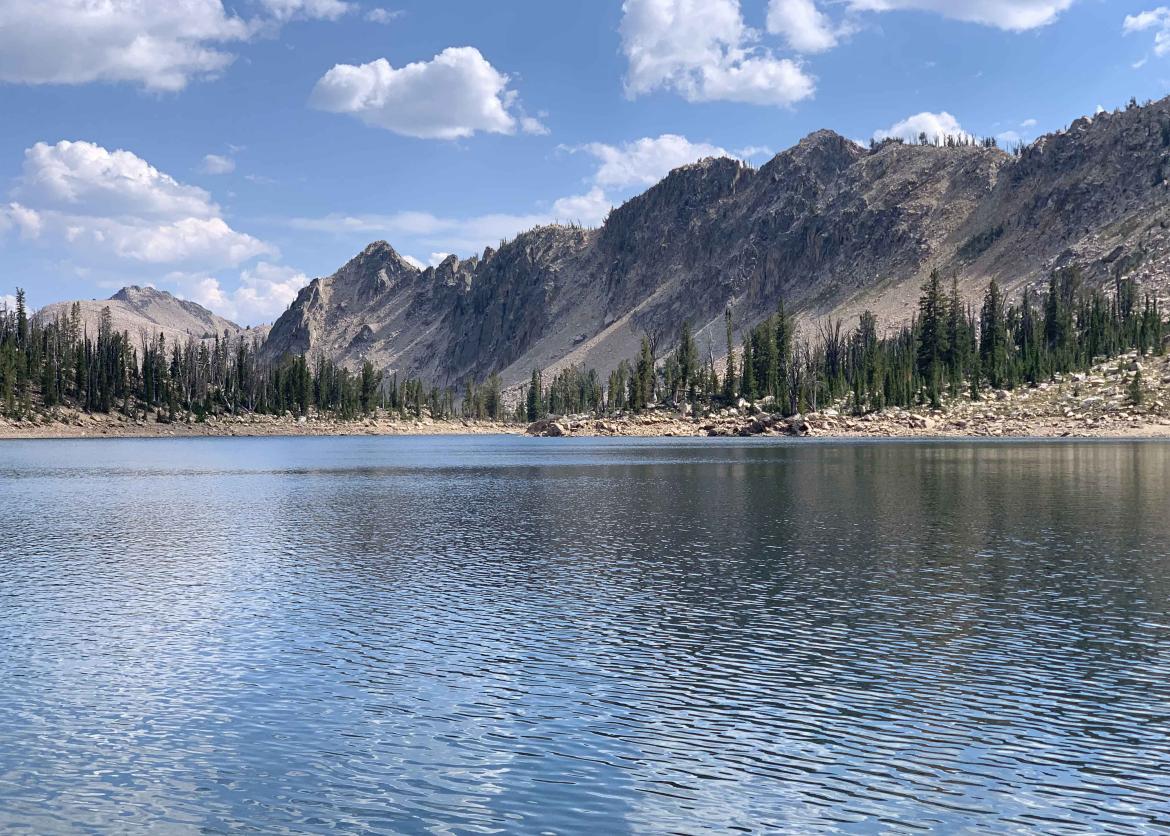 A jagged mountain range beside a lake.