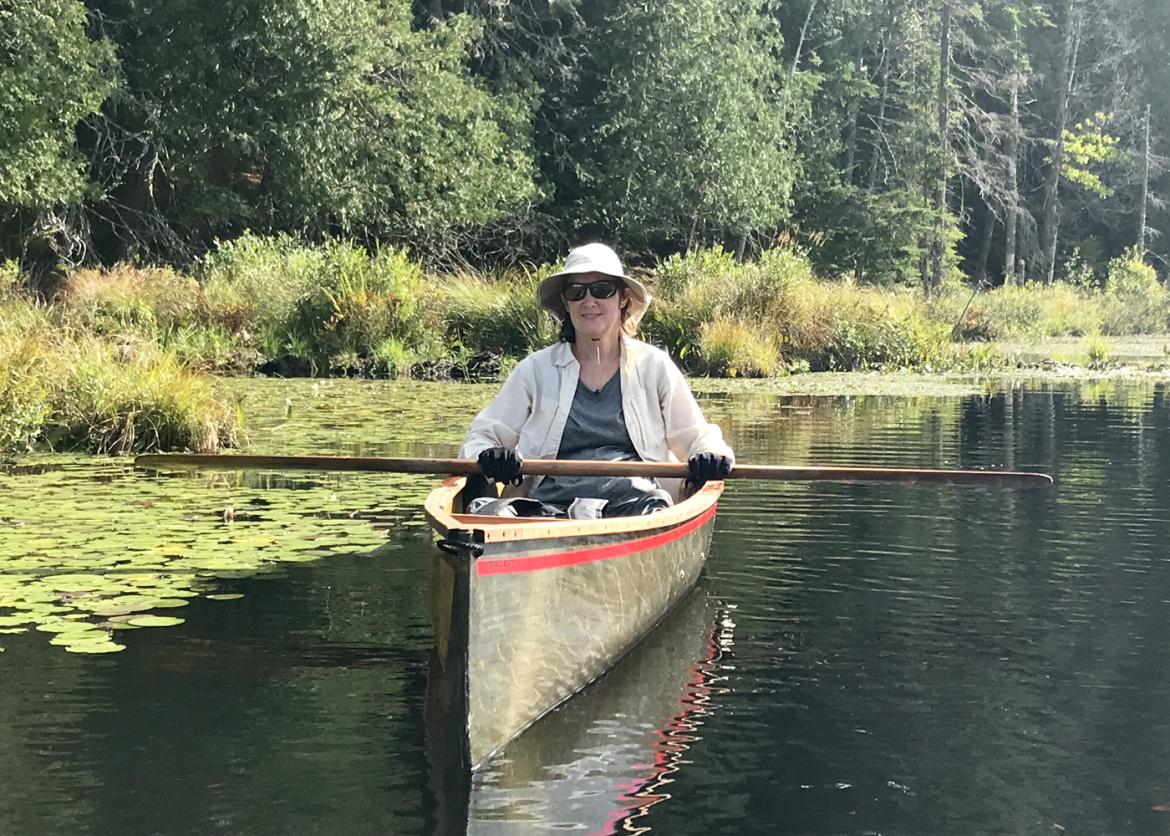 A woman holding a paddle on a canoe.