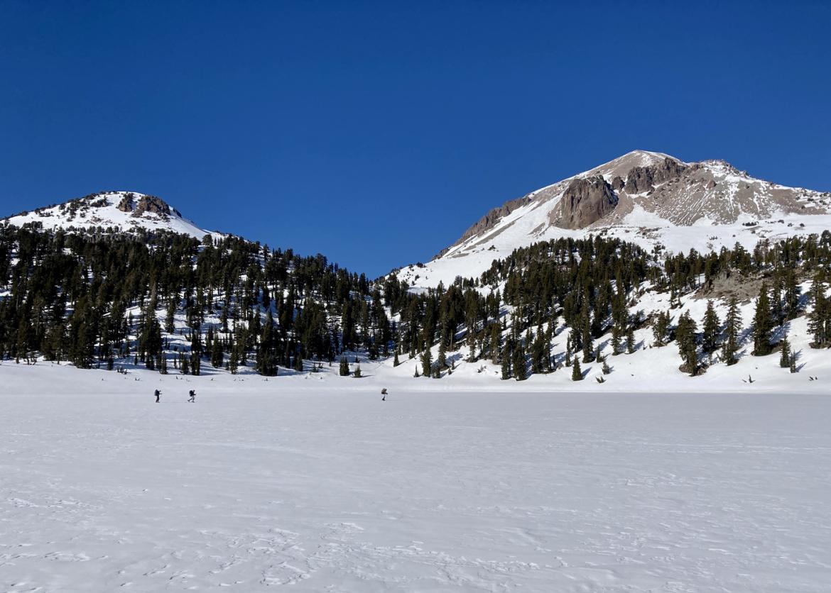 People far away from camera backcountry skiing at Lassen Volcanic National Park, California