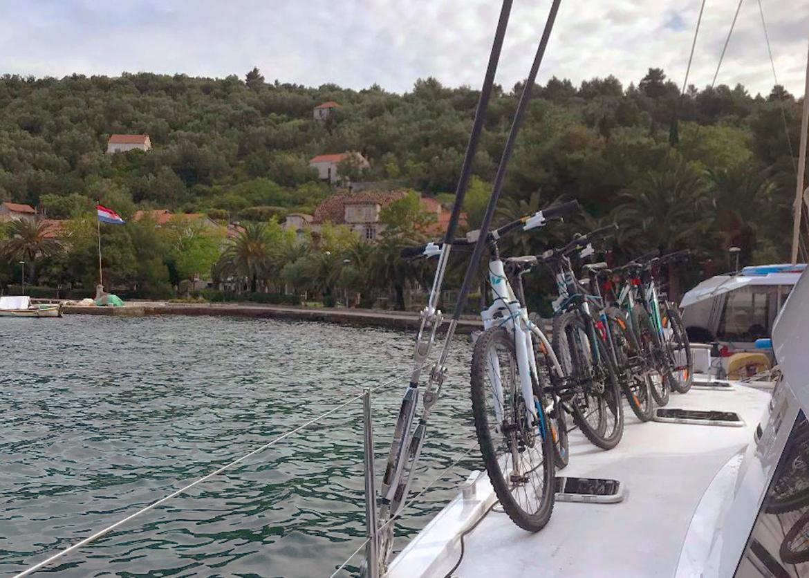 Trail bikes at the edge of a boat deck.  Red roof building dot a forested shore.