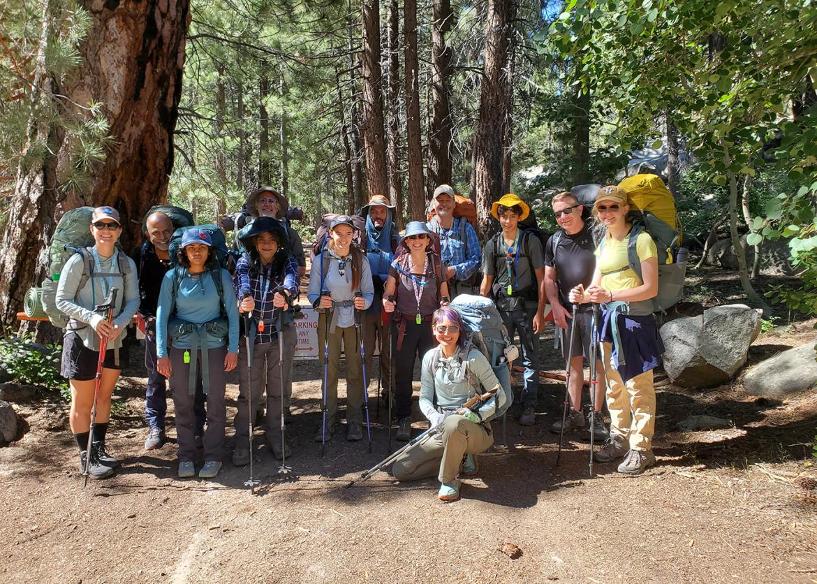 Group of teen participants with adult leaders, against the backdrop of a California forest.