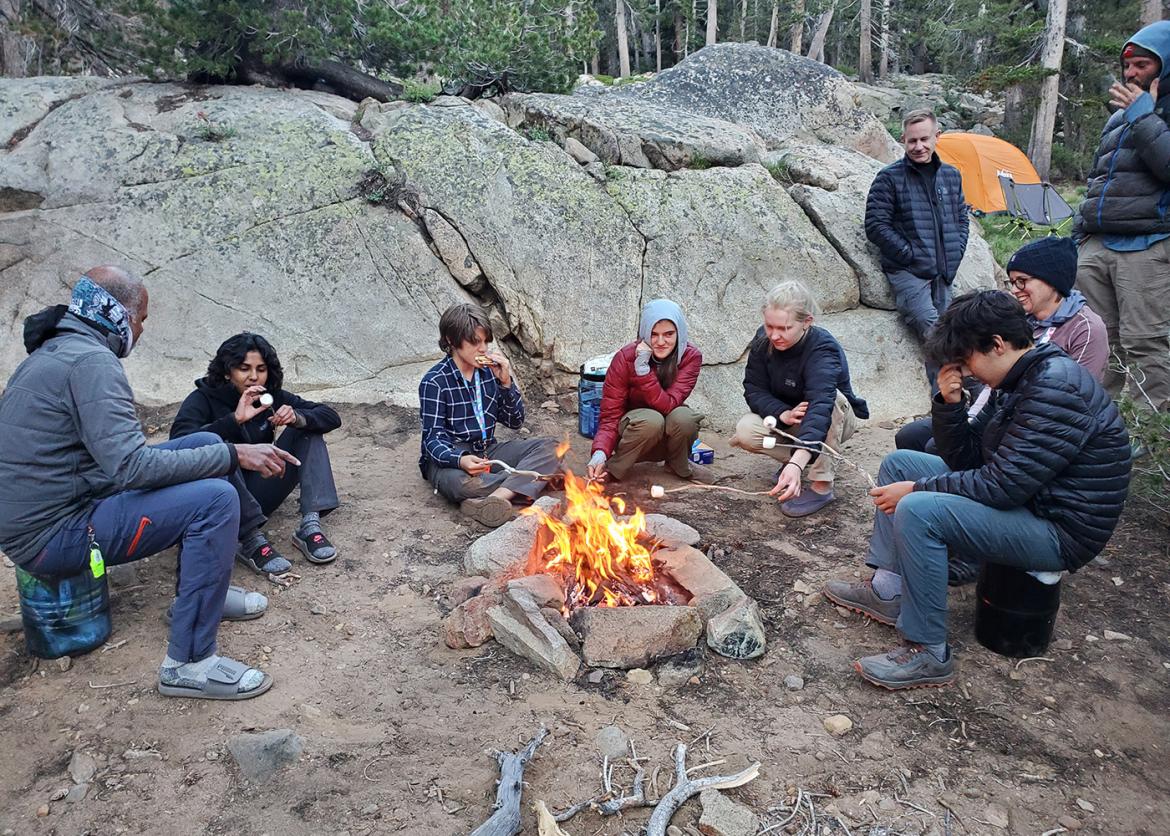 Group of teen participants around a campfire.