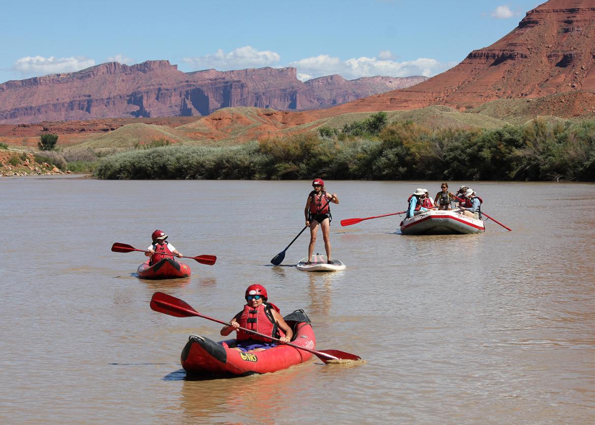 Trip participants raft, paddle, and SUP on a river in Moab