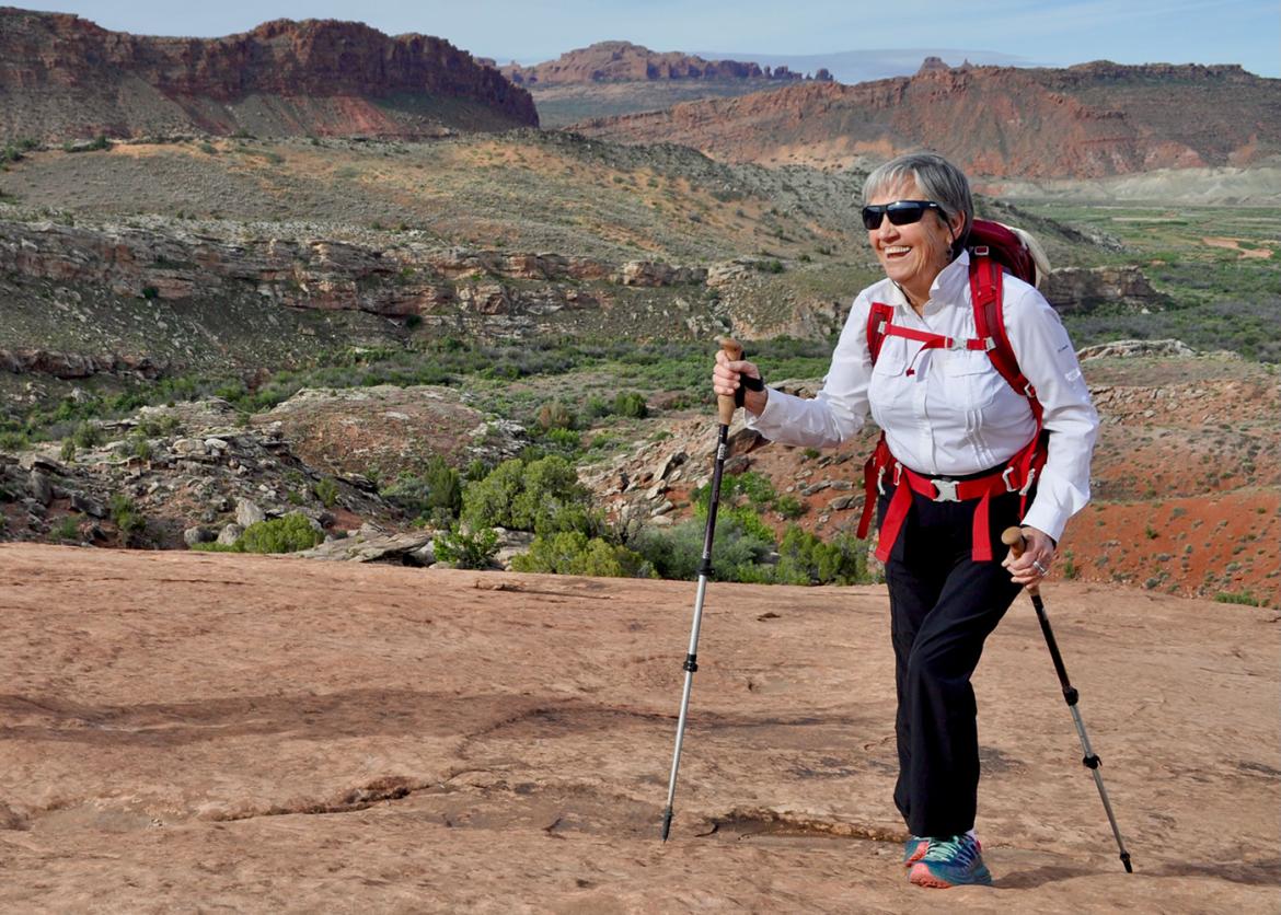 Woman hiking with trekking poles in a sprawling canyon landscape