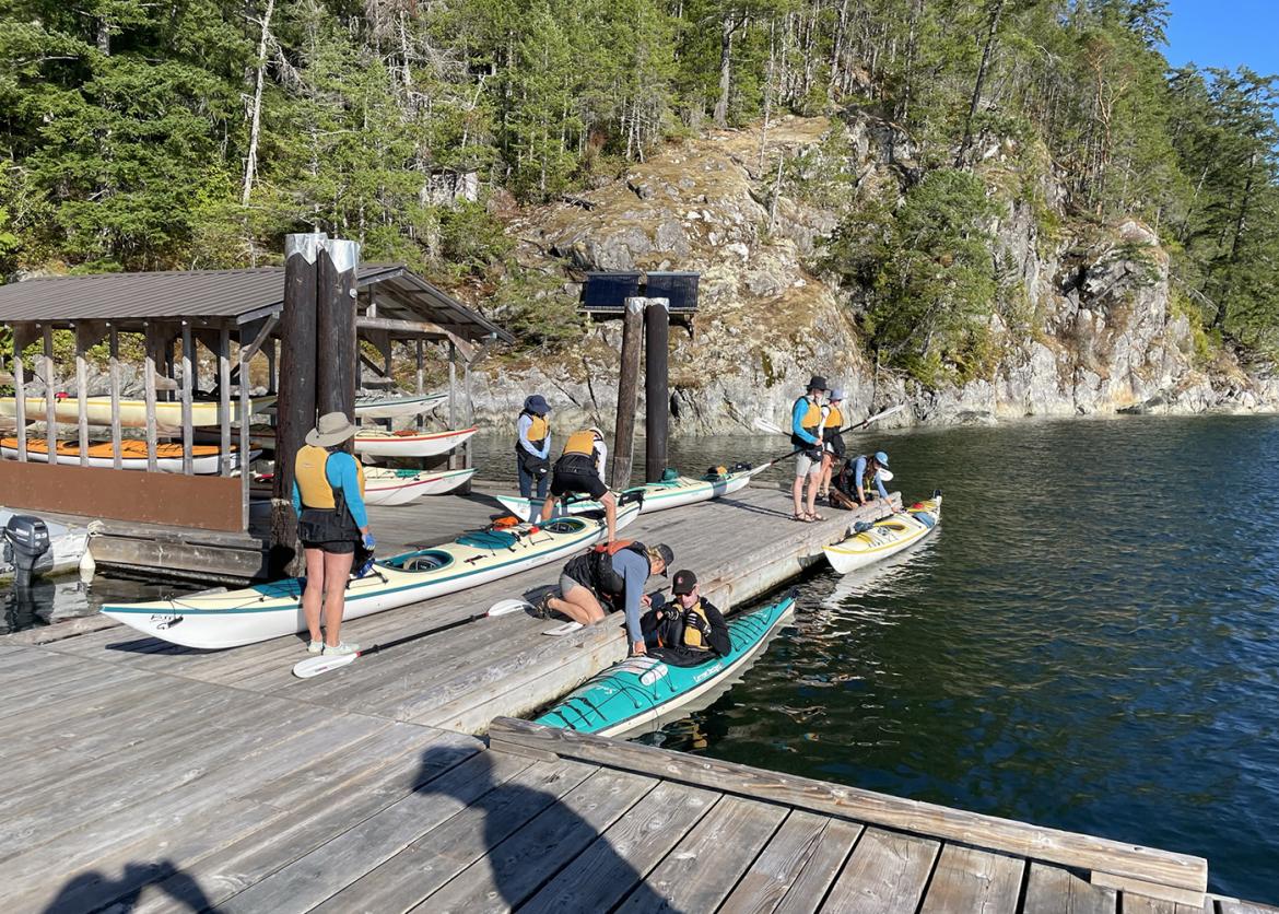 Trip participants on a dock over the water with forest in the background.