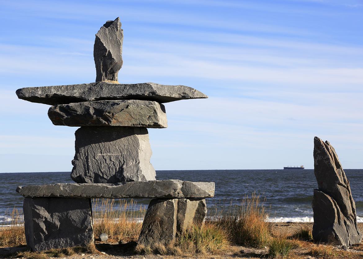 Inuksuk on west shore of Hudson Bay with a cargo ship in distance.
