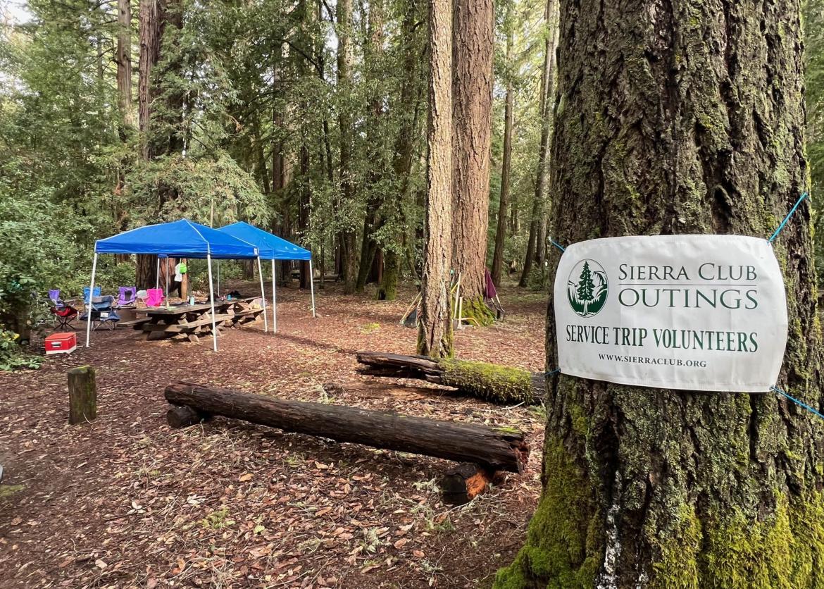 A campground labeled Sierra Club Service Trip Volunteers by a hung sign.