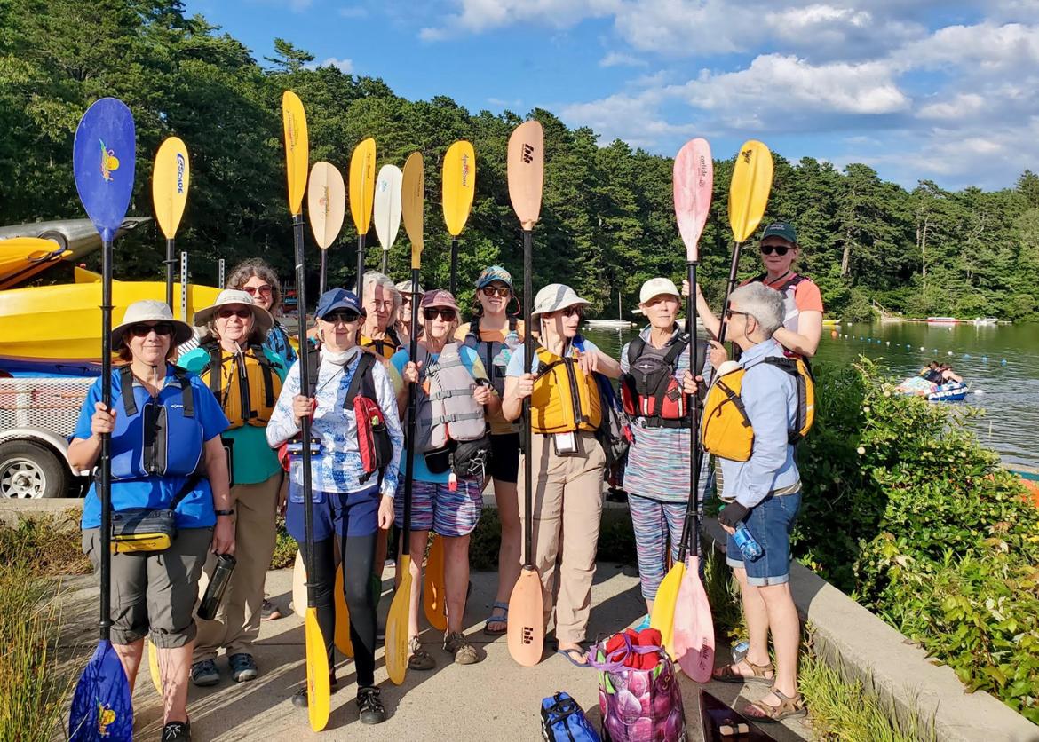 Trip participants posing for the camera, holding oars vertically.