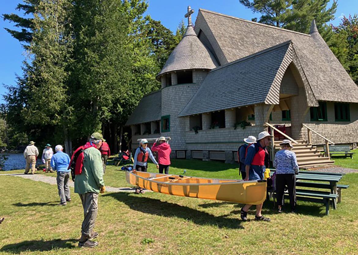 Trip participants carrying canoes in front of lodge 