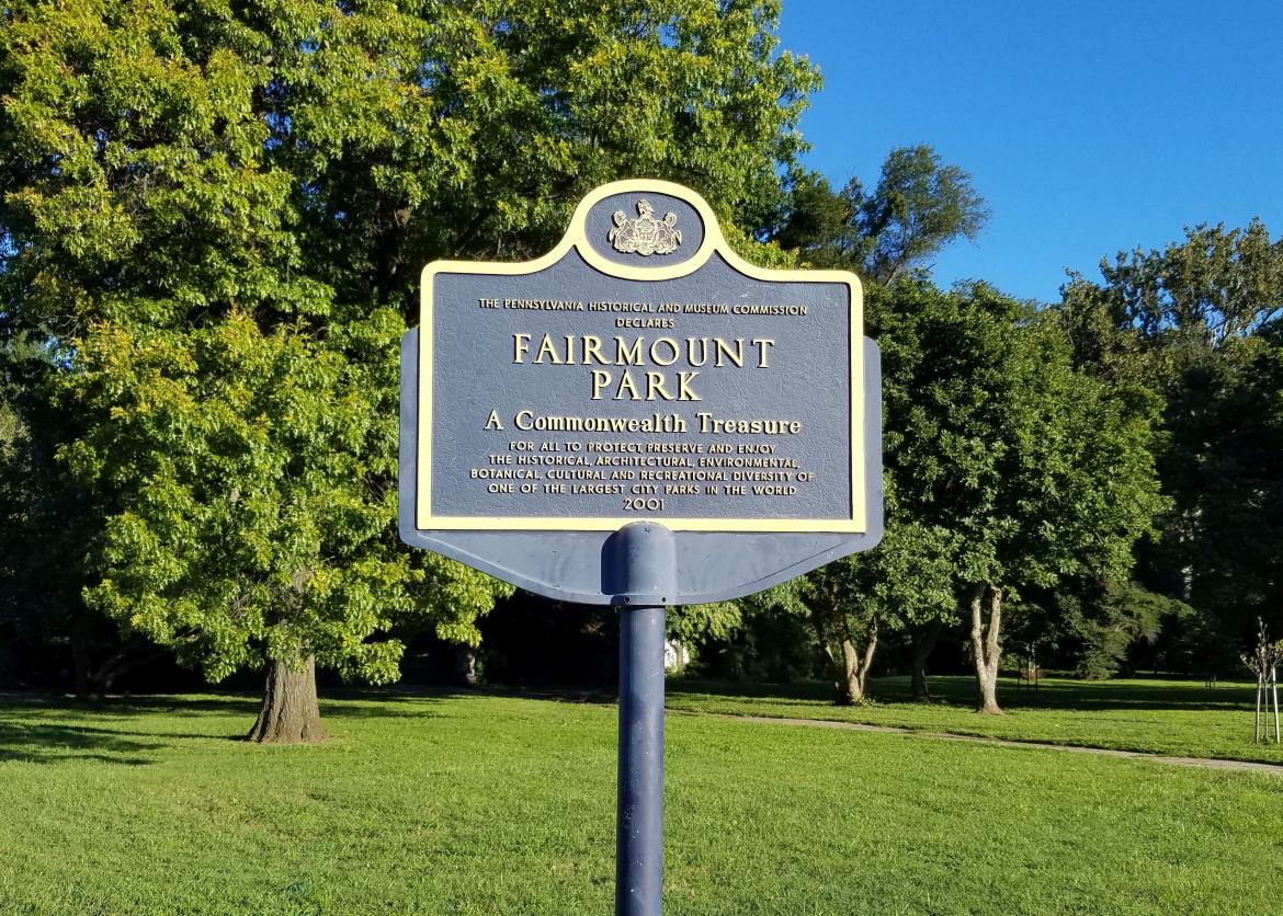 A park sign on a sunny day, it reads "Fairmount Park A Commonwealth Treasure."