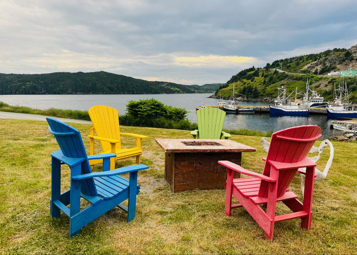 Colorful adirondack chairs around a firepit by the water